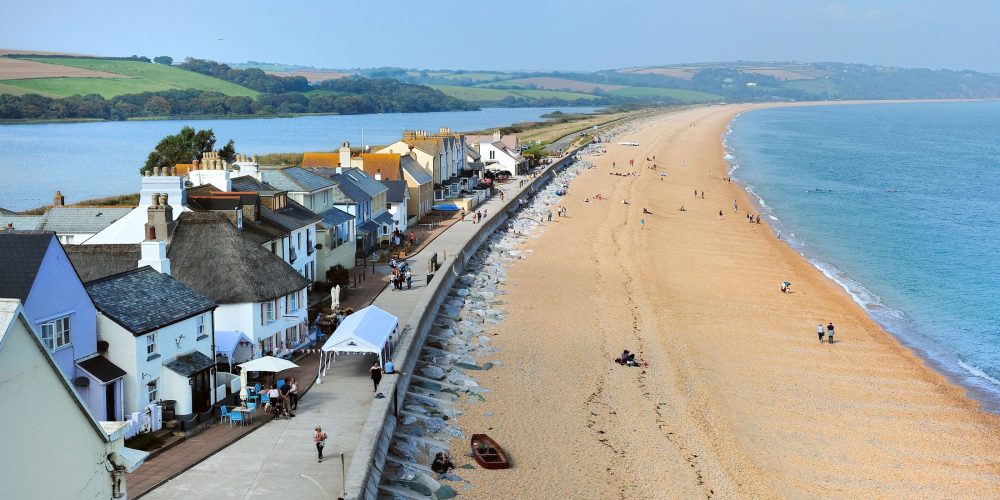 Looking North from Torcross along Slapton Line at low tide with people on the beach