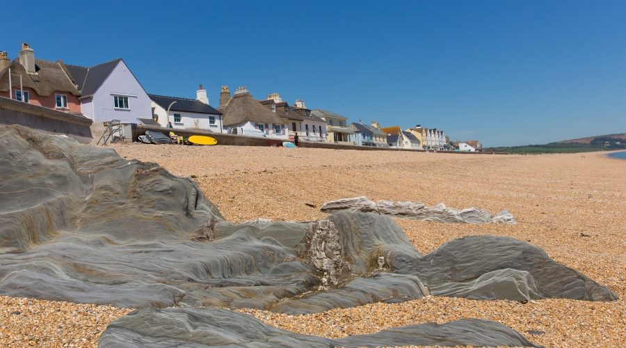 Looking up from the foreshore at Torcross - grey slate rocks in the foreground looking towards Torcross promenade